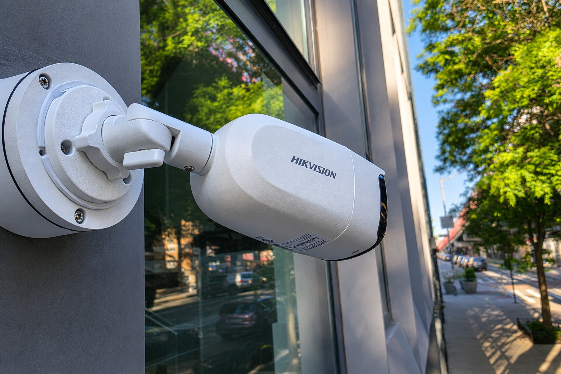 White exterior bullet security camera mounted beside a building window